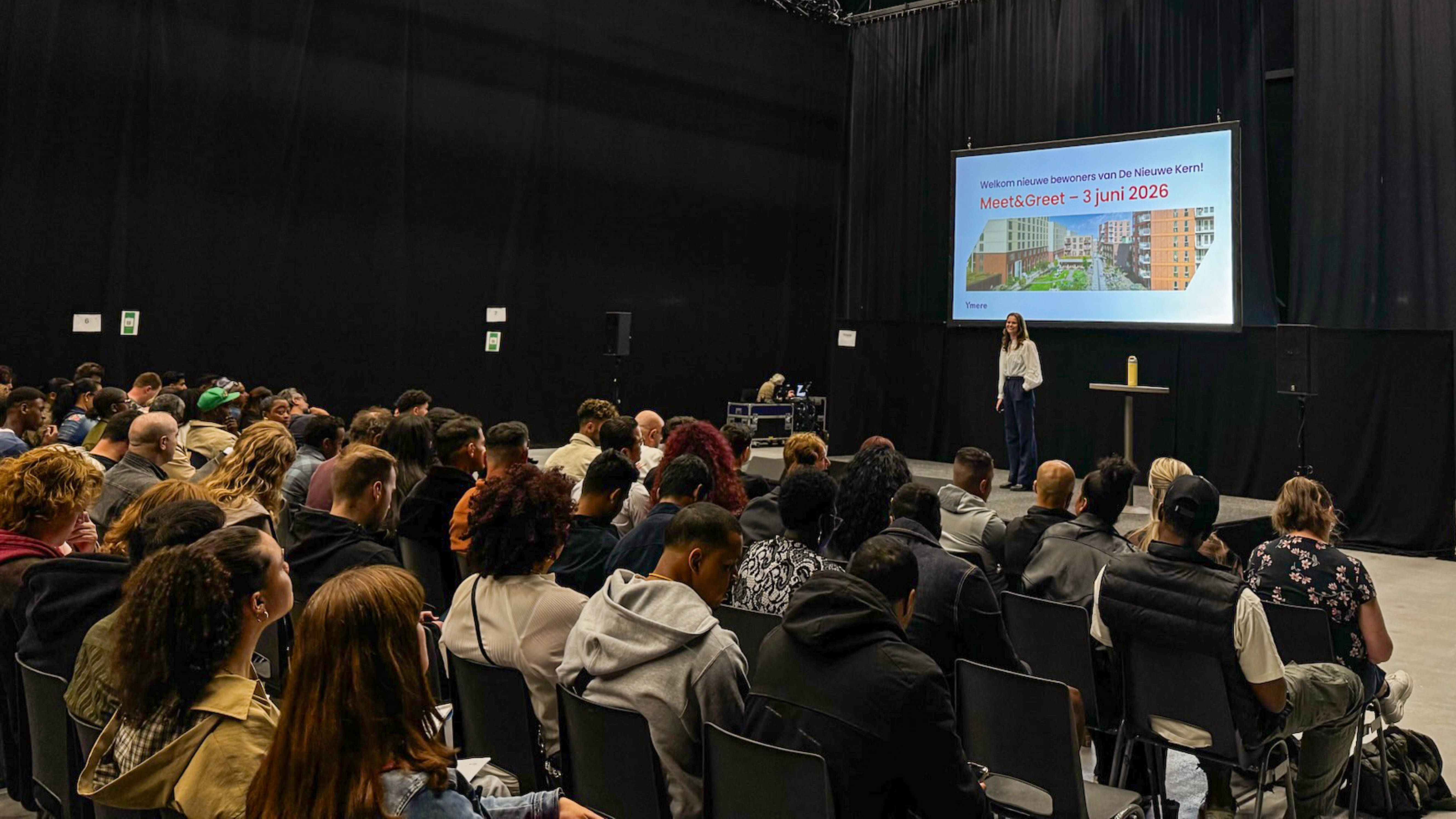 De zaal luistert aandachtig over het wonen in De Nieuwe Kern